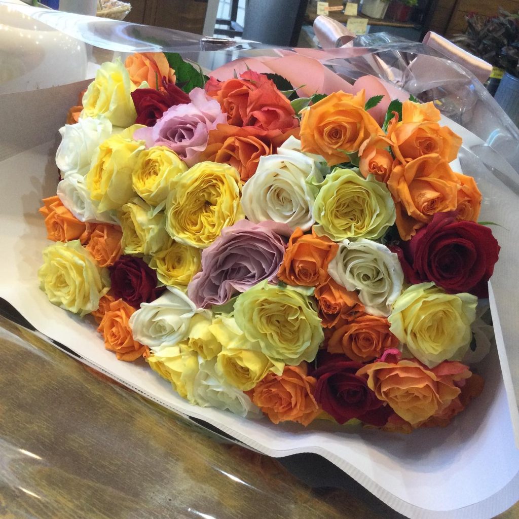 かわいいカラーのバラを集めた花束を
